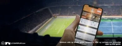 Mobiltelefon med LeoVegas Sports foran en fotballbane